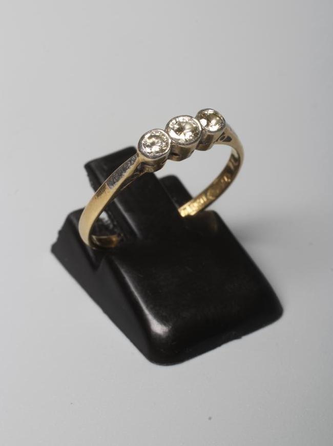 A THREE STONE DIAMOND RING, the old brilliant cut stones in rub over settings to a plain shank Image