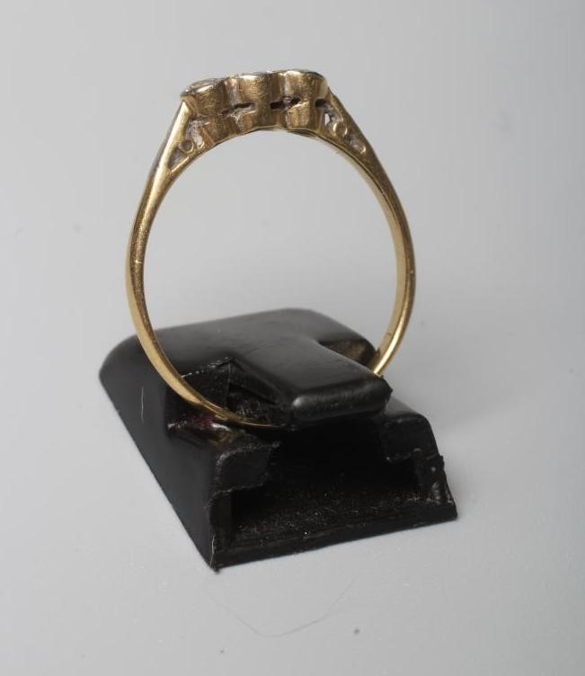 A THREE STONE DIAMOND RING, the old brilliant cut stones in rub over settings to a plain shank Image