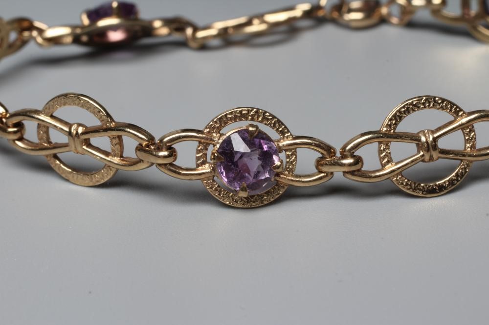 AN AMETHYST BRACELET, the 9ct gold snaffle links claw set with five round facet cut stones, Image