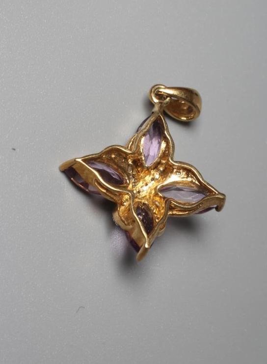AN AMETHYST AND DIAMOND PENDANT, the four pear cut amethysts claw set to a central pave diamond set Image