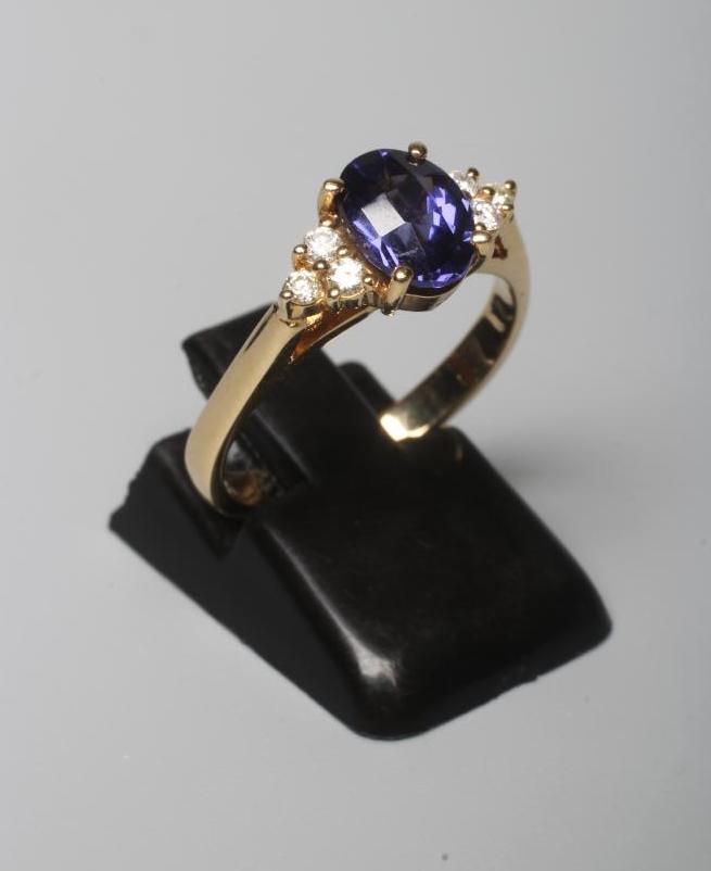 A TANZANITE DRESS RING, the oval facet cut stone claw set to shoulders each point set with three Image