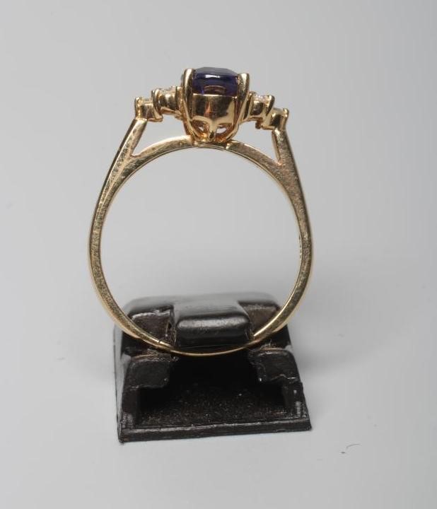 A TANZANITE DRESS RING, the oval facet cut stone claw set to shoulders each point set with three Image