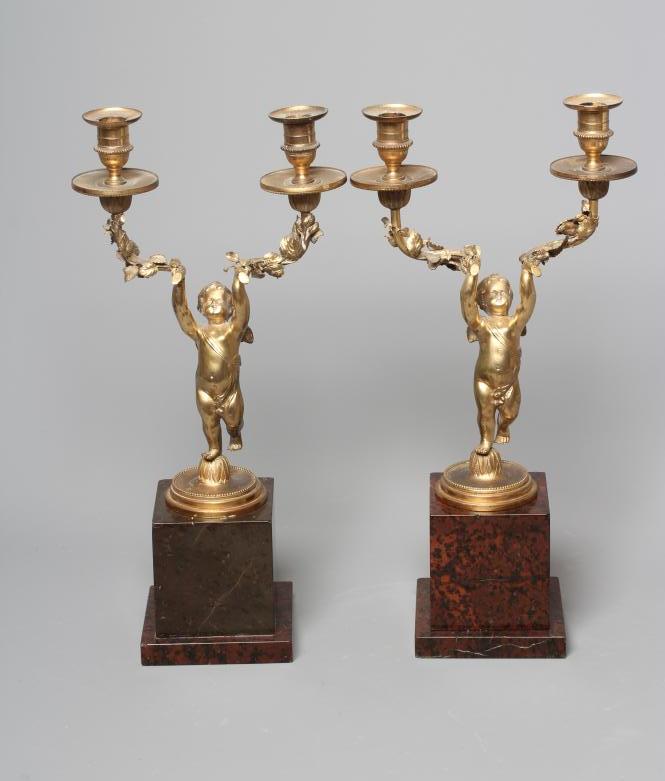 A PAIR OF ORMOLU CHERUB AND FOLIATE TWO BRANCH CANDELABRA raised on square marble plinth bases, each Image