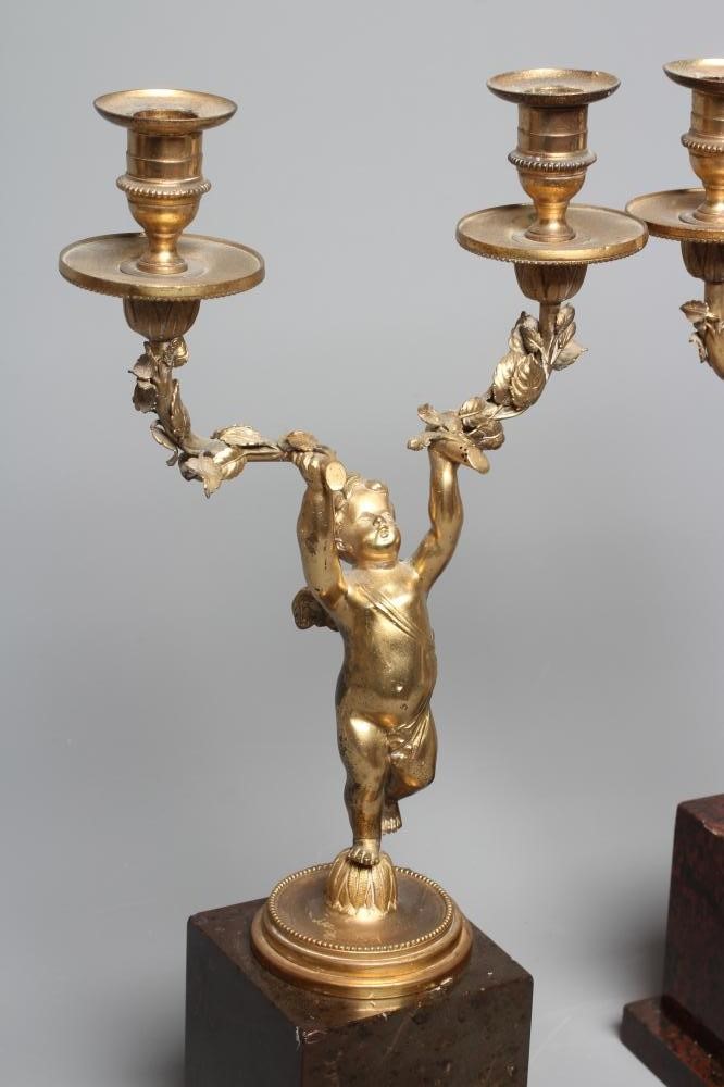 A PAIR OF ORMOLU CHERUB AND FOLIATE TWO BRANCH CANDELABRA raised on square marble plinth bases, each Image