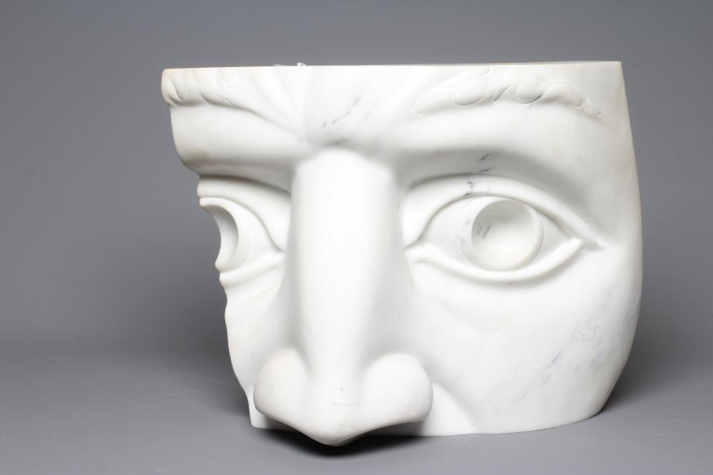 A ROMAN STYLE CONCAVE WHITE MARBLE SCULPTURE, in the form of a fragment of a face, with incised leaf Image