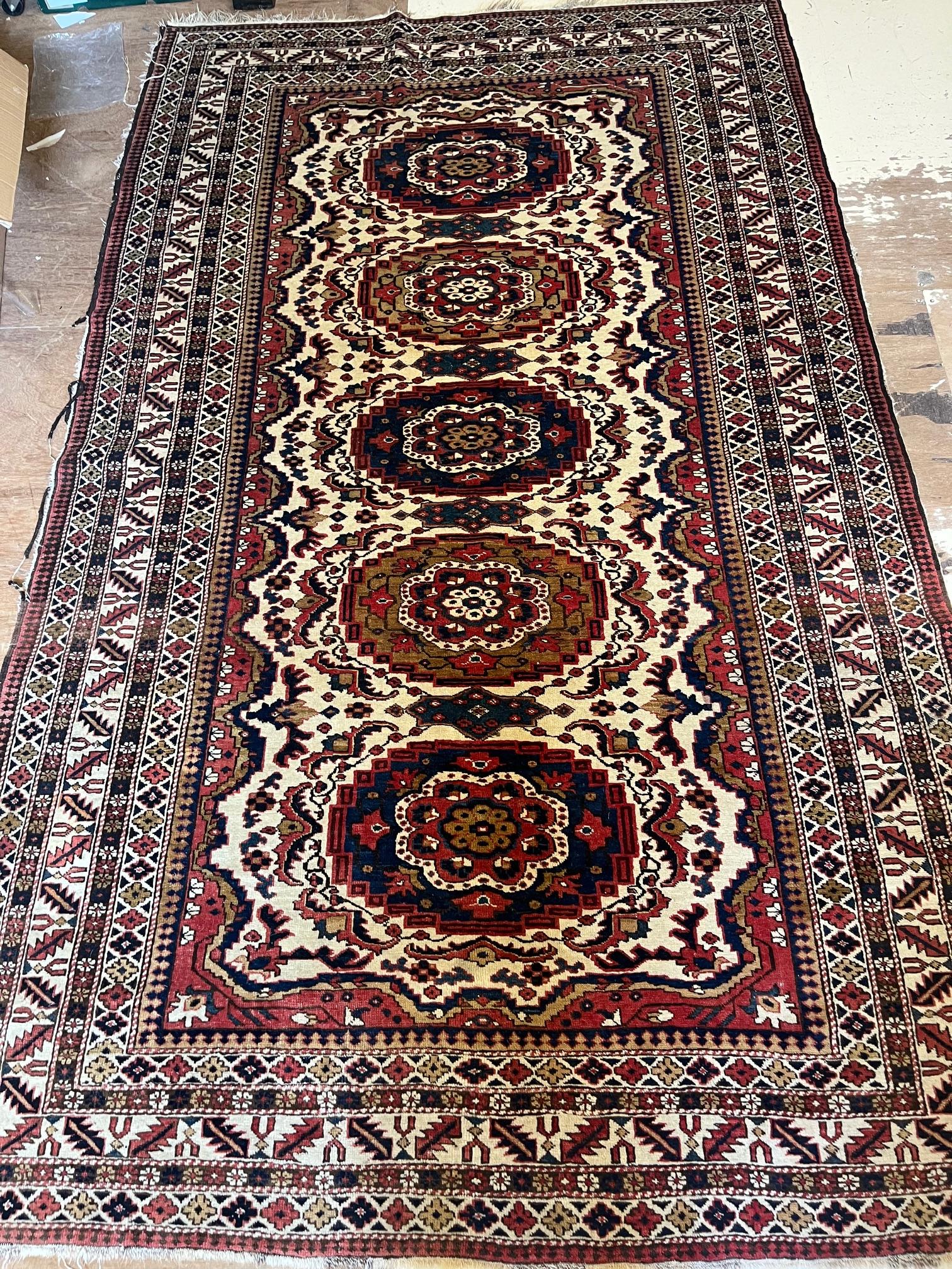 AN ANTIQUE CAUCASIAN RUG, early 20th century, the ivory and red field with five guls in indigo and Image