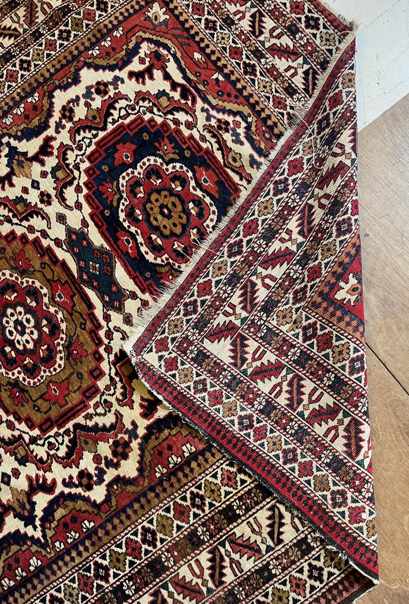 AN ANTIQUE CAUCASIAN RUG, early 20th century, the ivory and red field with five guls in indigo and Image