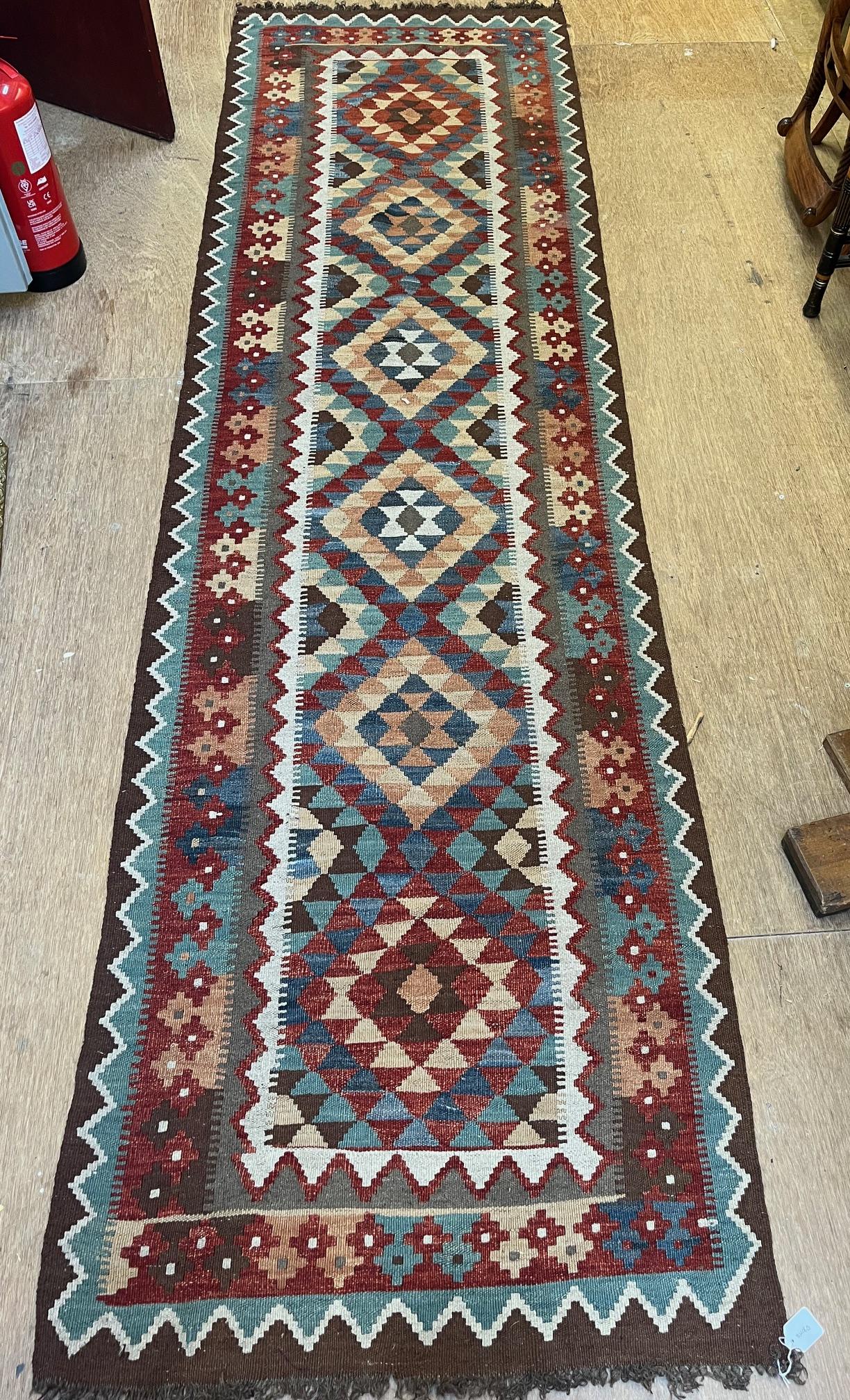 AN AFGHAN KILM RUNNER, modern, the ivory field with five diamond patterned guls in pale green, blue Image