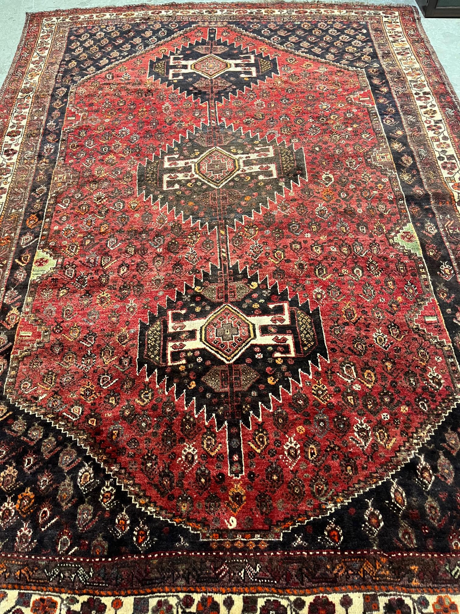 A KURDISH WOOL RUG, the claret field with three indigo serrated guls, similar spandrels Image
