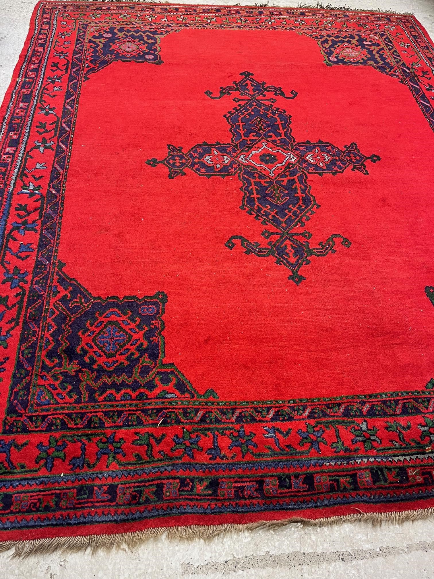 A TURKISH USHAK RED GROUND WOOL CARPET Image