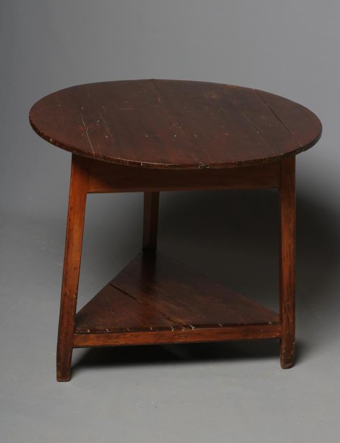 A STAINED PINE CRICKET TABLE, 19th century, the circular plank top and plain frieze on square Image