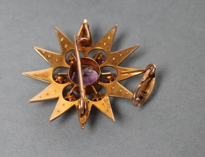 AN EDWARDIAN STAR BROOCH/PENDANT centred by an open back collet set circular facet cut amethyst Image