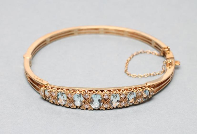 AN AQUAMARINE AND DIAMOND STIFF HINGED BANGLE Image