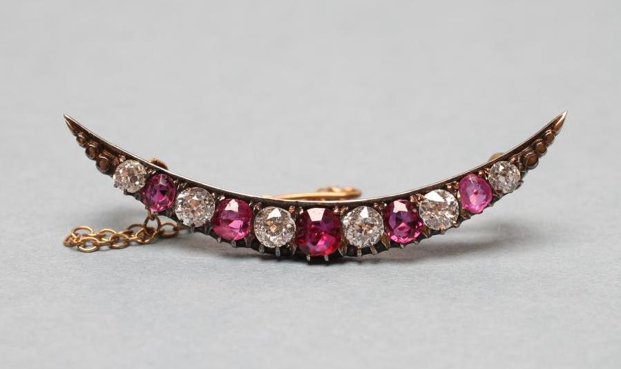 AN EDWARDIAN RUBY AND DIAMOND CRESCENT BROOCH alternately claw set with five graduating rubies and Image