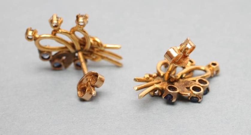A PAIR OF SAPPHIRE AND DIAMOND EAR STUDS as stylised looped sprays claw set with four small diamonds Image