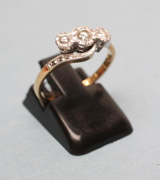 A THREE STONE DIAMOND CROSSOVER RING Image