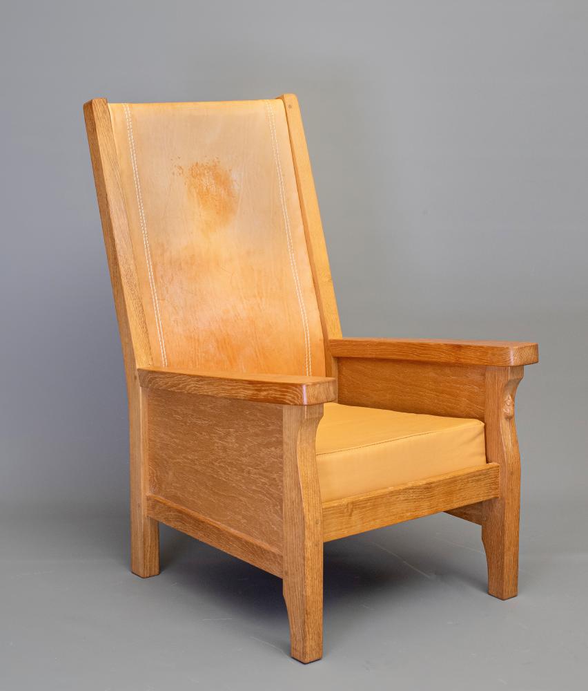 AN ADZED OAK SMOKER'S CHAIR by Robert Thompson with cow hide back and loose cushion Image