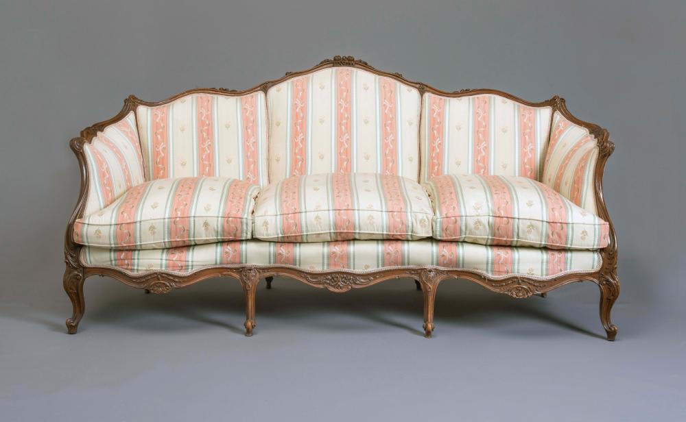 A LOUIS XVI STYLE WALNUT FRAMED SOFA of serpentine outline carved with flowers and scroll work and Image