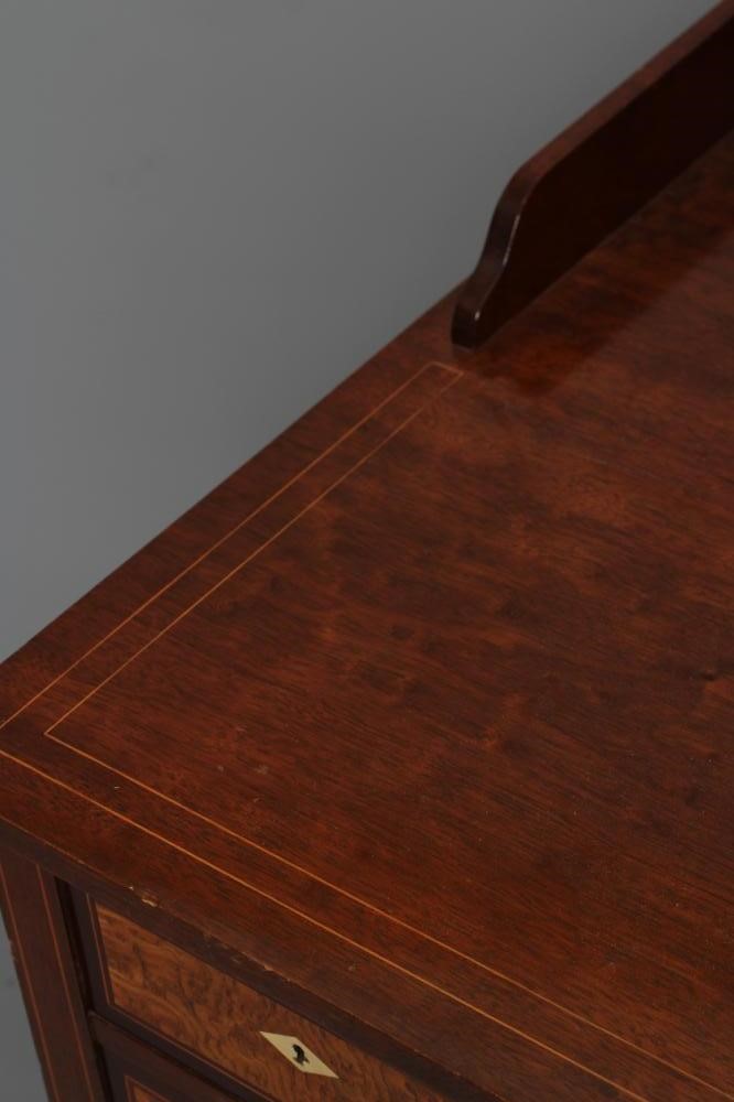 AN EDWARDIAN MAHOGANY KNEEHOLE DRESSING TABLE of oblong form with stringing and three quarter Image