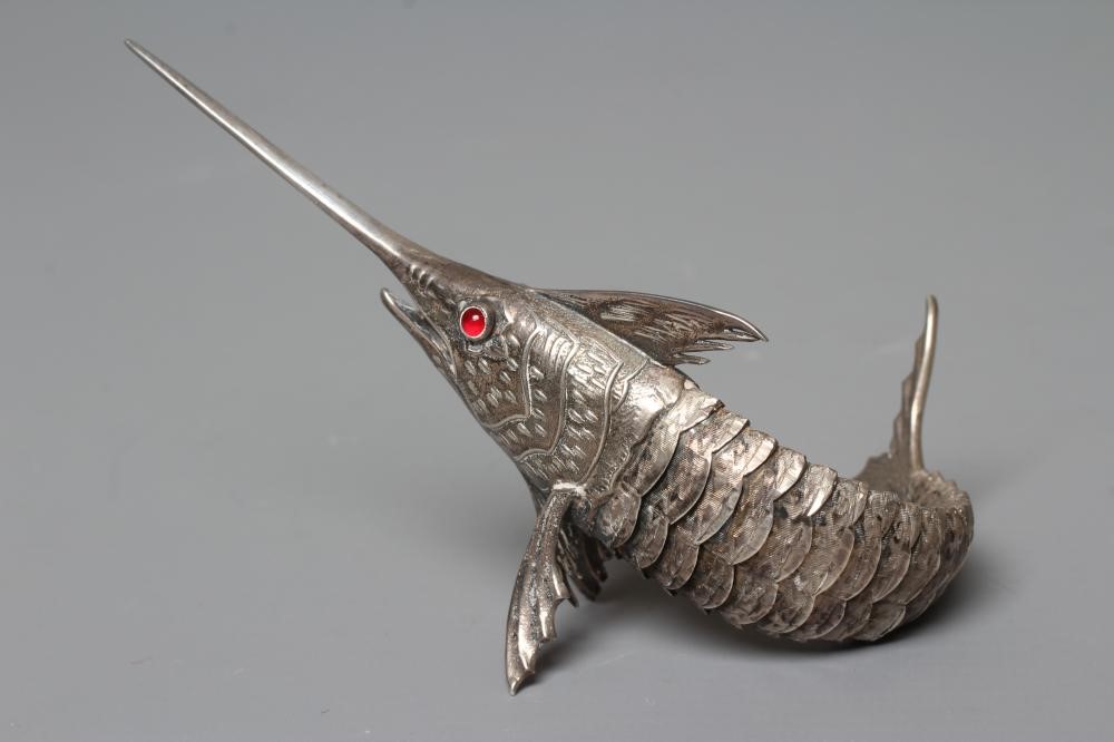A SPANISH SILVER ARTICULATED SWORDFISH with chased detailing and collet set ruby glass cabochon Image