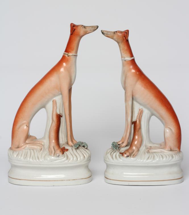 A PAIR OF VICTORIAN STAFFORDSHIRE POTTERY GREYHOUNDS modelled seated with free-standing fore-legs Image