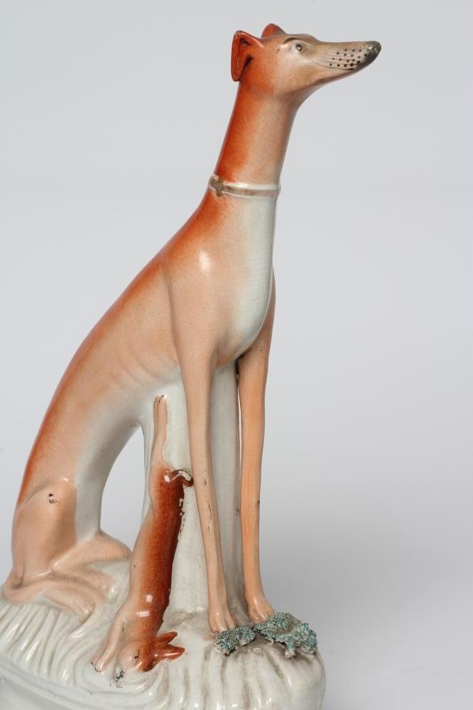 A PAIR OF VICTORIAN STAFFORDSHIRE POTTERY GREYHOUNDS modelled seated with free-standing fore-legs Image