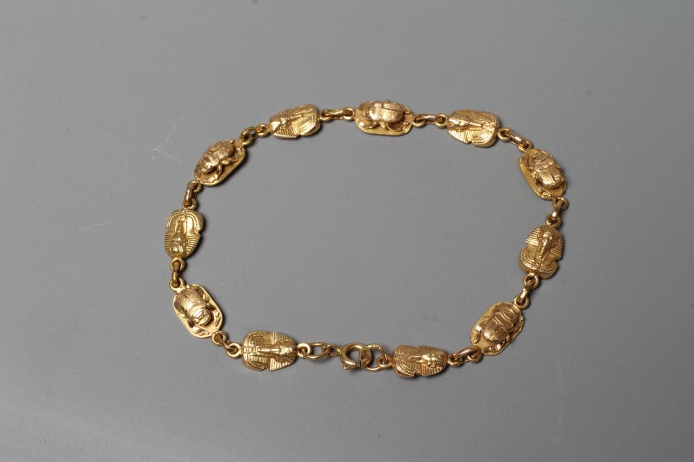AN EGYPTIANESQUE BRACELET, stamped 750, with scarab and face mask cast links and spring ring Image