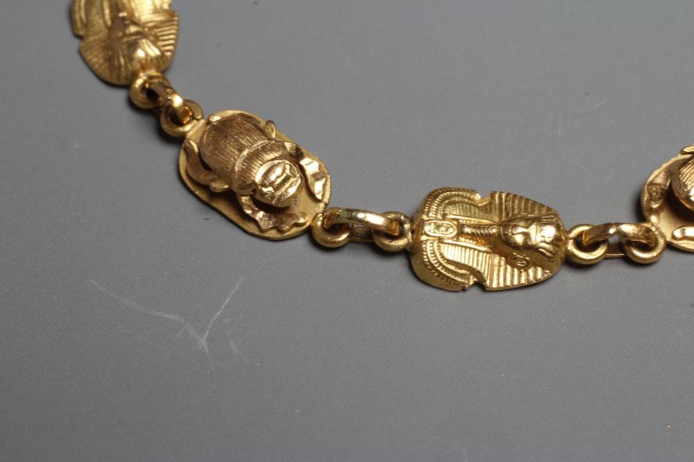 AN EGYPTIANESQUE BRACELET, stamped 750, with scarab and face mask cast links and spring ring Image