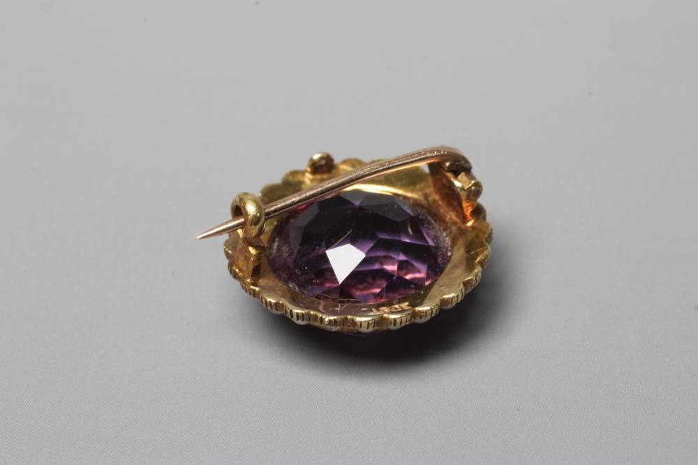 AN EDWARDIAN AMETHYST AND SEED PEARL BROOCH, the circular facet cut amethyst collet set to a border Image