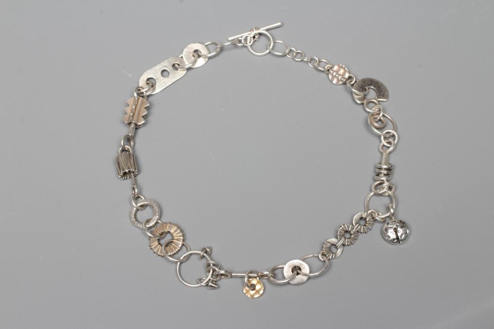 A SILVER NECKLACE BY ADELE TAYLOR, the plain circular links hung with cast 'found' objects, Image