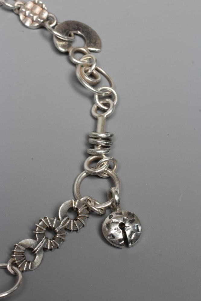 A SILVER NECKLACE BY ADELE TAYLOR, the plain circular links hung with cast 'found' objects, Image
