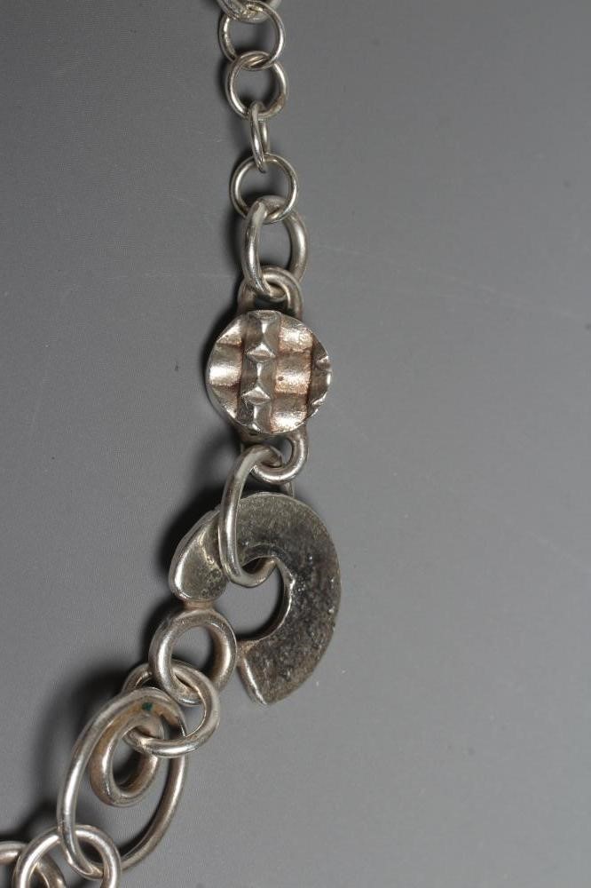 A SILVER NECKLACE BY ADELE TAYLOR, the plain circular links hung with cast 'found' objects, Image