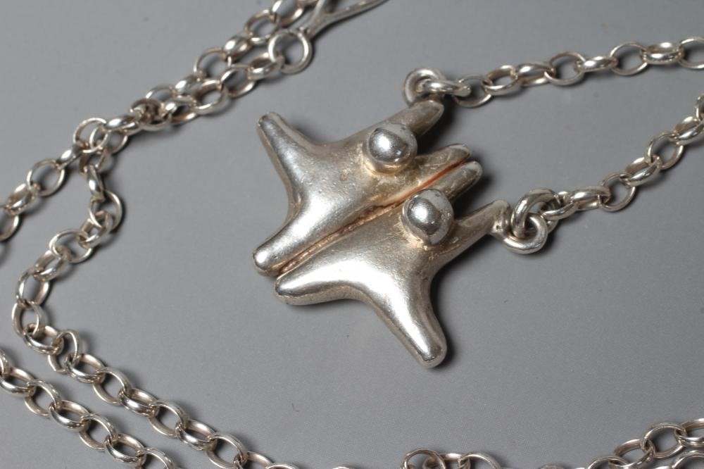 LEONARD AND ANNE EDGER- a silver pendant cast as two stylised figures suspended from a Sterling Image