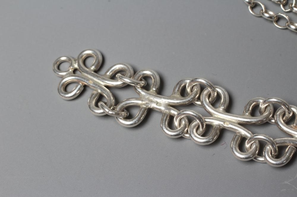 LEONARD AND ANNE EDGER- a silver pendant cast as two stylised figures suspended from a Sterling Image