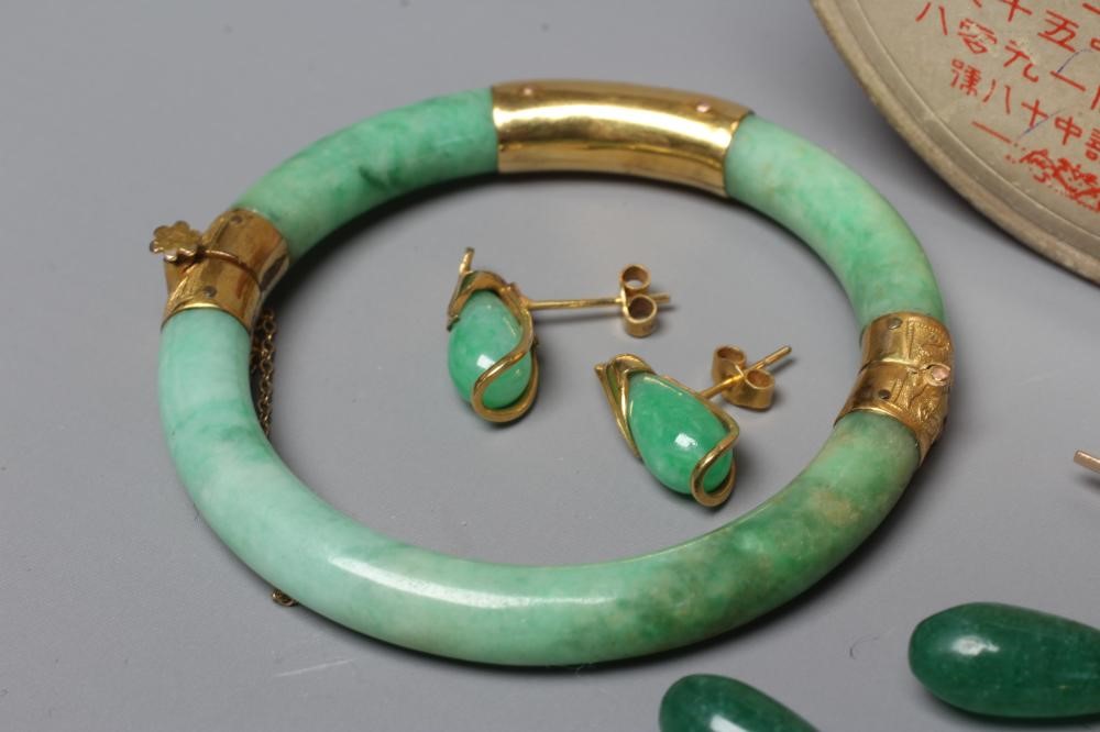 A CHINESE POLISHED JADE STIFF HINGED BANGLE of cylindrical form the chased mounts stamped 14 Image