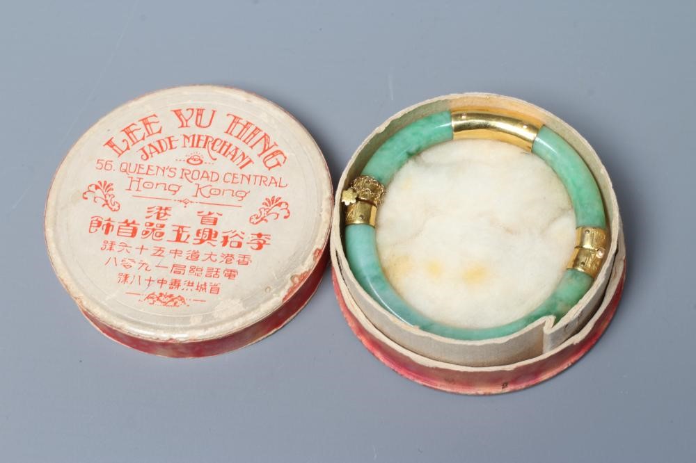 A CHINESE POLISHED JADE STIFF HINGED BANGLE of cylindrical form the chased mounts stamped 14 Image