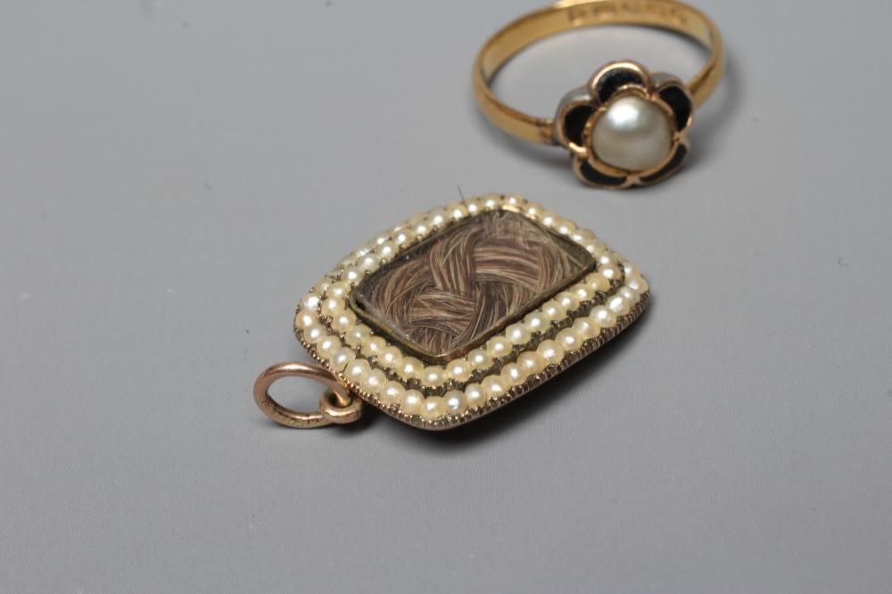 AN EARLY VICTORIAN MOURNING PENDANT of rounded oblong form with double seed pearl border enclosing a Image