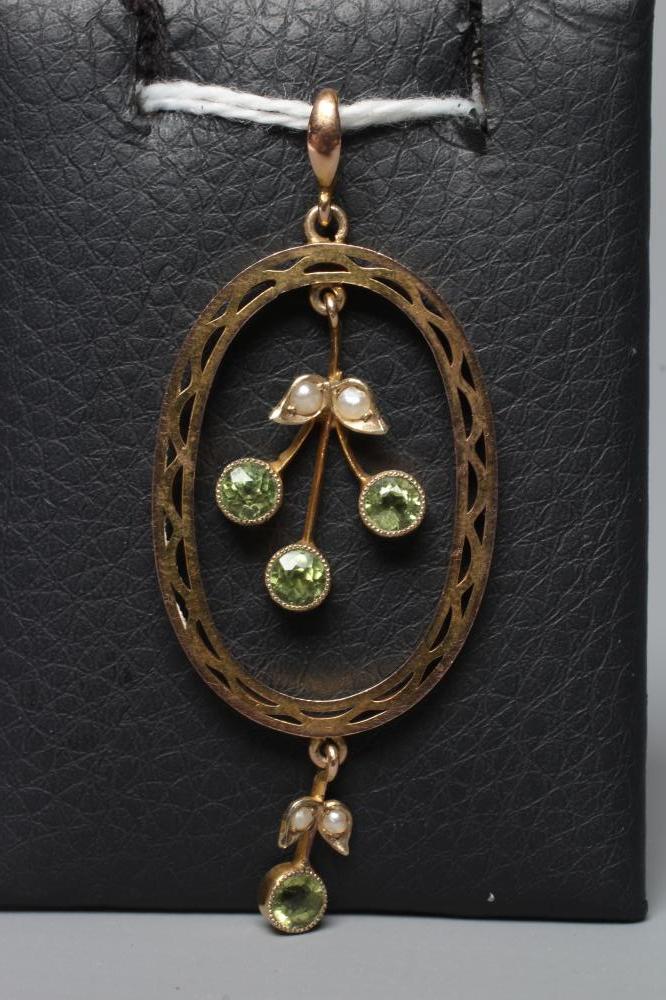 AN EDWARDIAN OPEN OVAL PENDANT centred by a trefoil of peridots with two seed pearl leaves, hung Image