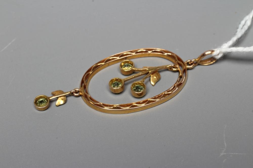 AN EDWARDIAN OPEN OVAL PENDANT centred by a trefoil of peridots with two seed pearl leaves, hung Image
