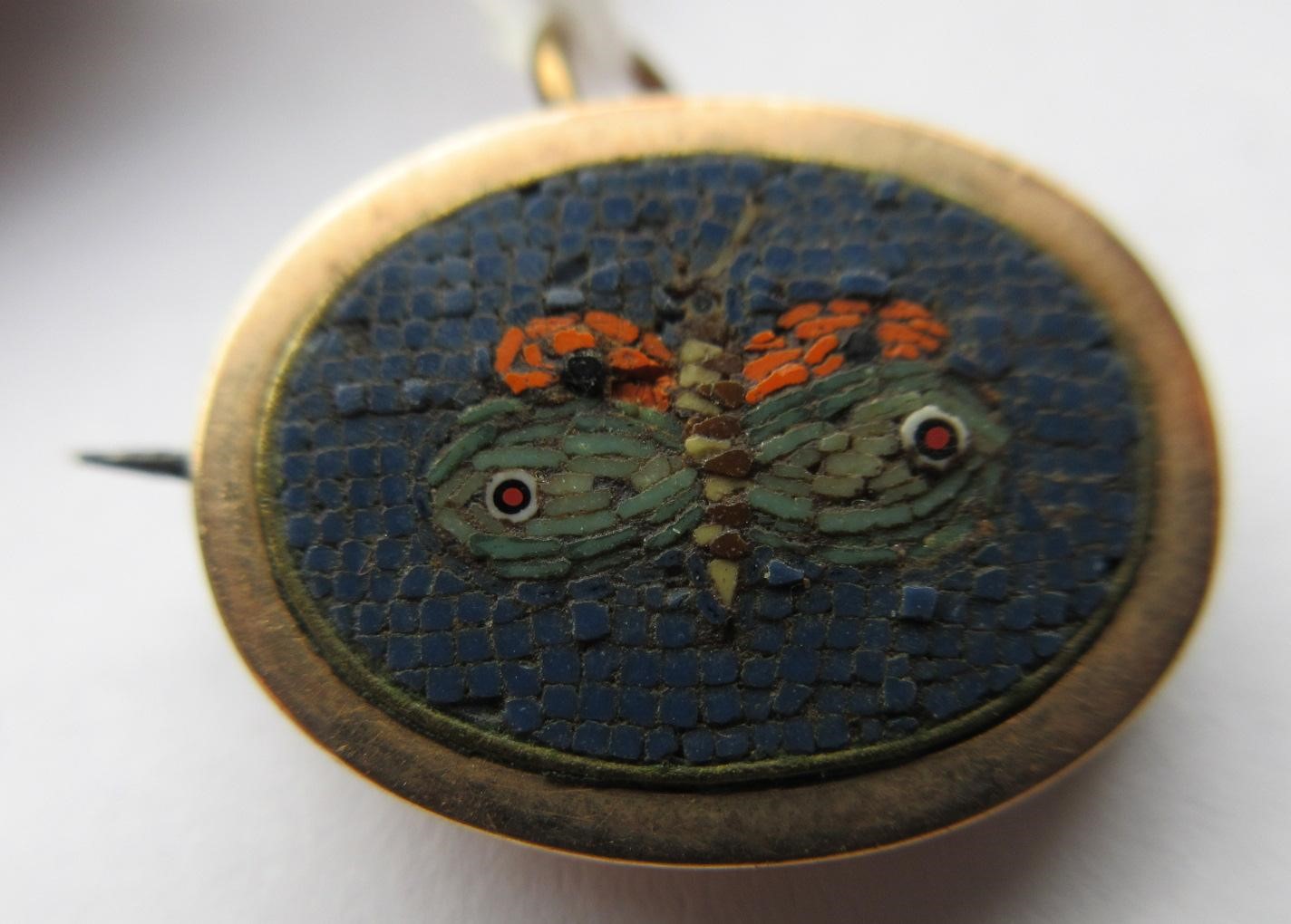 A VICTORIAN MICRO-MOSAIC OVAL MINIATURE BROOCH centred by a butterfly on a black ground Image