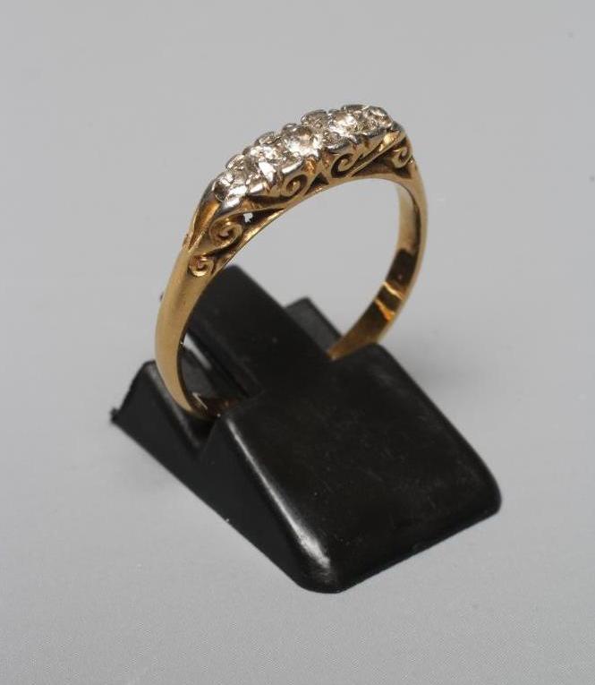 A LATE VICTORIAN FIVE STONE DIAMOND RING, the mix cut stones point set to carved mount and shoulders Image