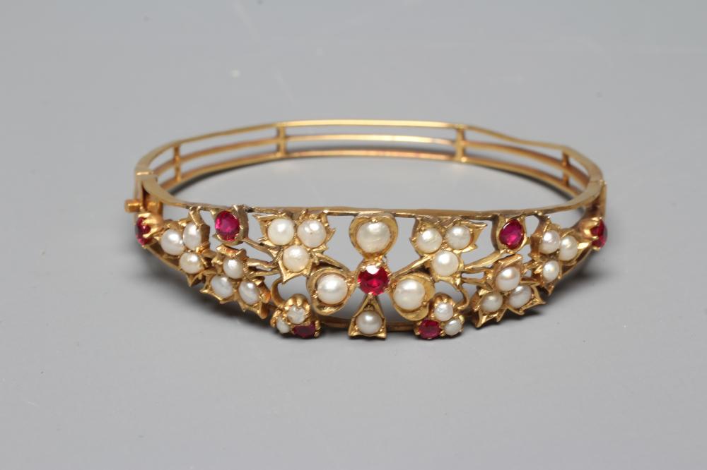 A LATE VICTORIAN STIFF HINGED BANGLE, the open upper section set with seven rubies and numerous Image