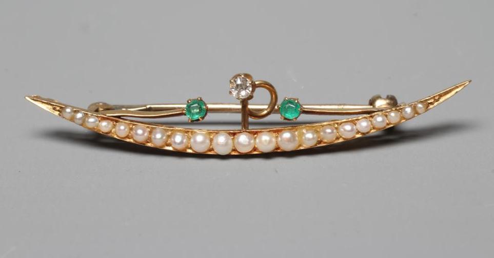 AN EDWARDIAN SEED PEARL CRESCENT BROOCH claw set with two facet cut small emeralds and a diamond on Image