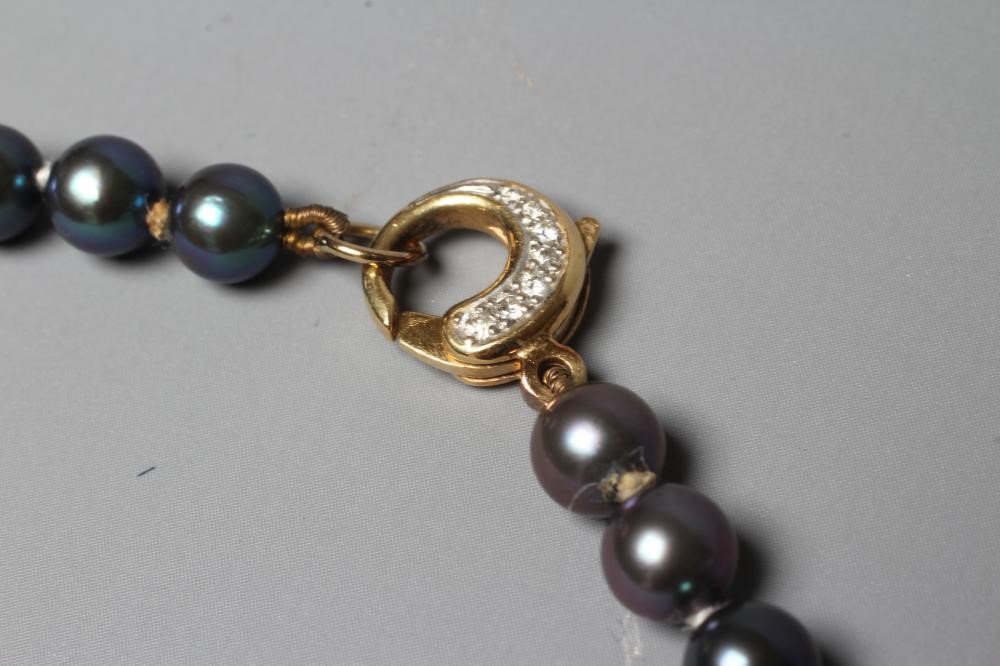 A SINGLE STRING OF BLACK CULTURED PEARLS, the circular clasp stamped 750 and point set with seven Image