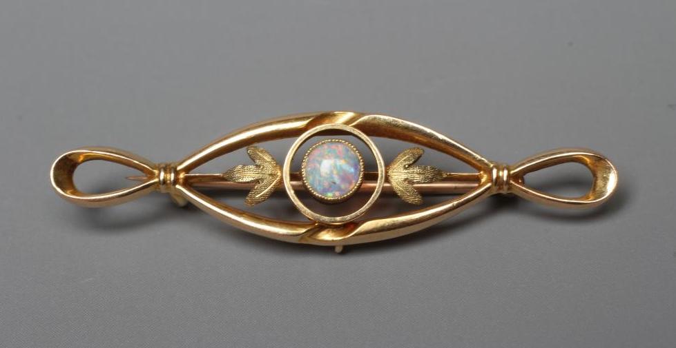 AN EDWARDIAN OPAL BROOCH, the central open oval panel collet set with an oval cabochon polished opal Image