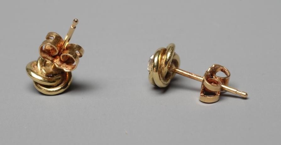 A PAIR OF SOLITAIRE DIAMOND EAR STUDS, the brilliant cut stones claw set to an 18ct gold knot (Est. Image