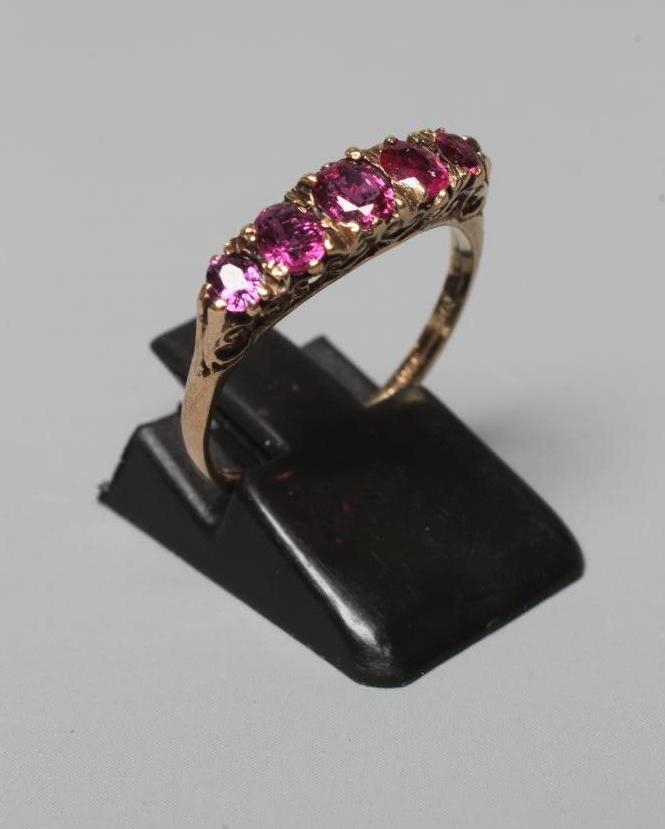 A FIVE STONE GARNET RING, the graduating oval facet cut stones in a bark mount on a plain 9ct gold Image