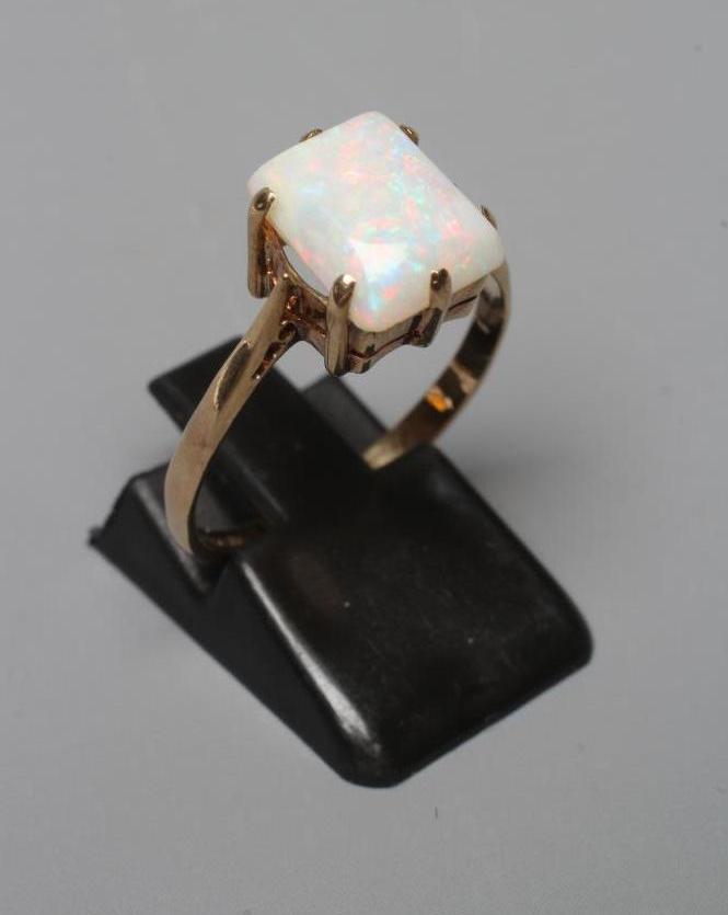 AN OPAL DRESS RING, the square cut cabochon stone claw set to a plain 9ct gold shank, Birmingham Image
