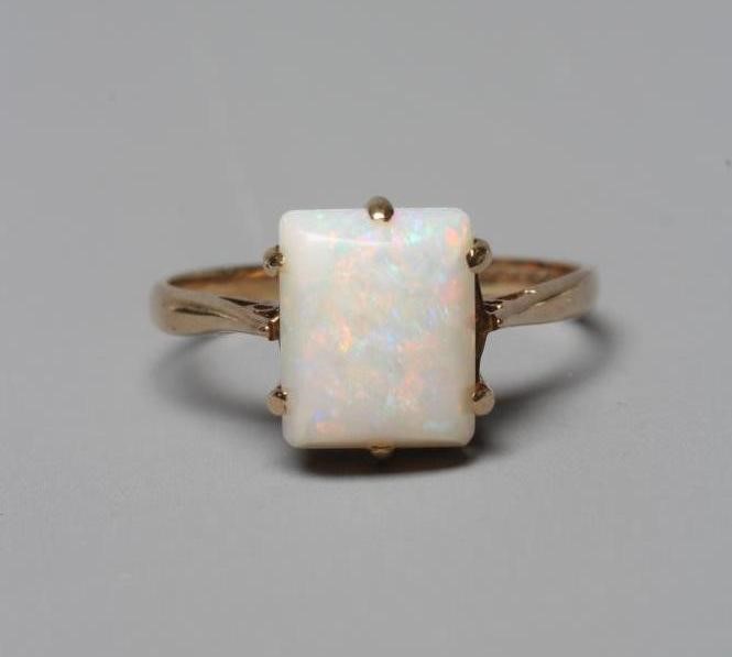 AN OPAL DRESS RING, the square cut cabochon stone claw set to a plain 9ct gold shank, Birmingham Image