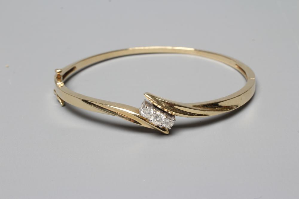 A DIAMOND STIFF HINGED BANGLE, the upper section with three brilliant cut stones in an open Image